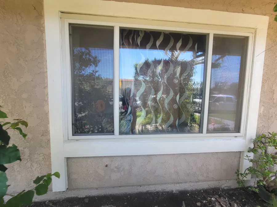 Fresh stucco patch across the panel below a window sill, with the trim repainted white